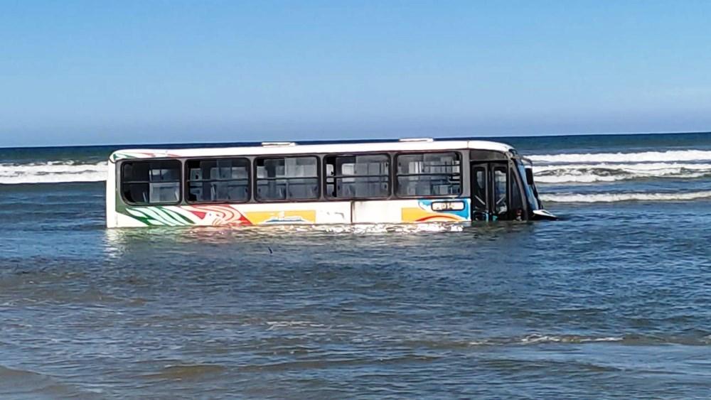 Ônibus fica atolado em praia durante ressaca e chega a ficar 80% coberto pela água