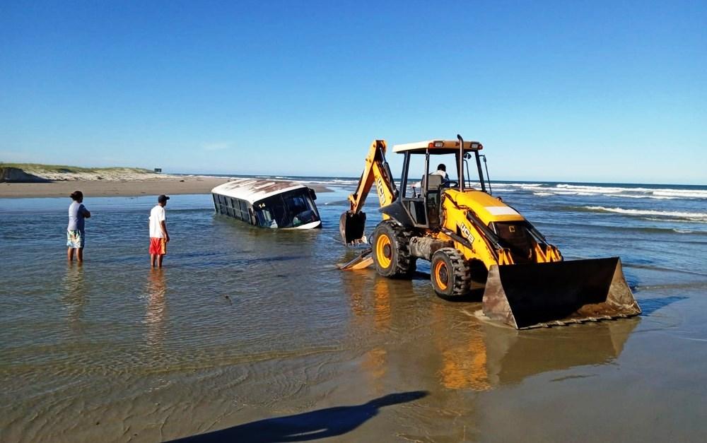 Ônibus fica atolado em praia durante ressaca e chega a ficar 80% coberto pela água